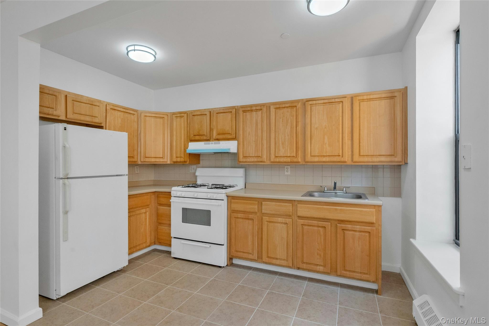 2023 Belmont Avenue, Unit 5A Bronx, NY 10457 - Photo 6 of 19 a kitchen with a sink a refrigerator and cabinets