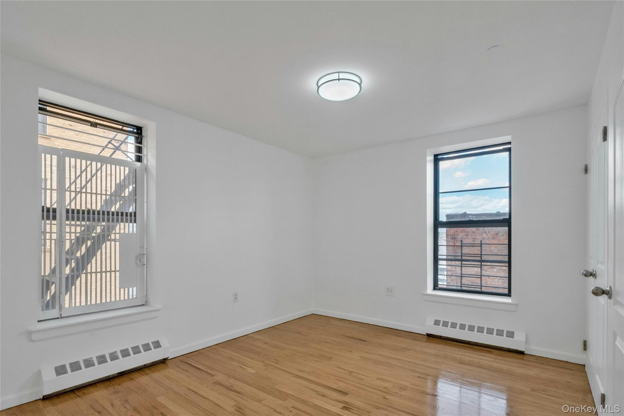 2023 Belmont Avenue, Unit 5A Bronx, NY 10457 - Photo 10 of 19 a view of an empty room with wooden floor and a window