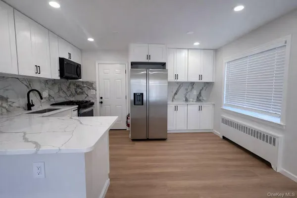 a kitchen with stainless steel appliances kitchen island granite countertop a refrigerator and a sink