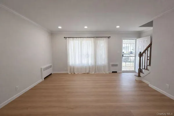 a view of an empty room with wooden floor and stairs