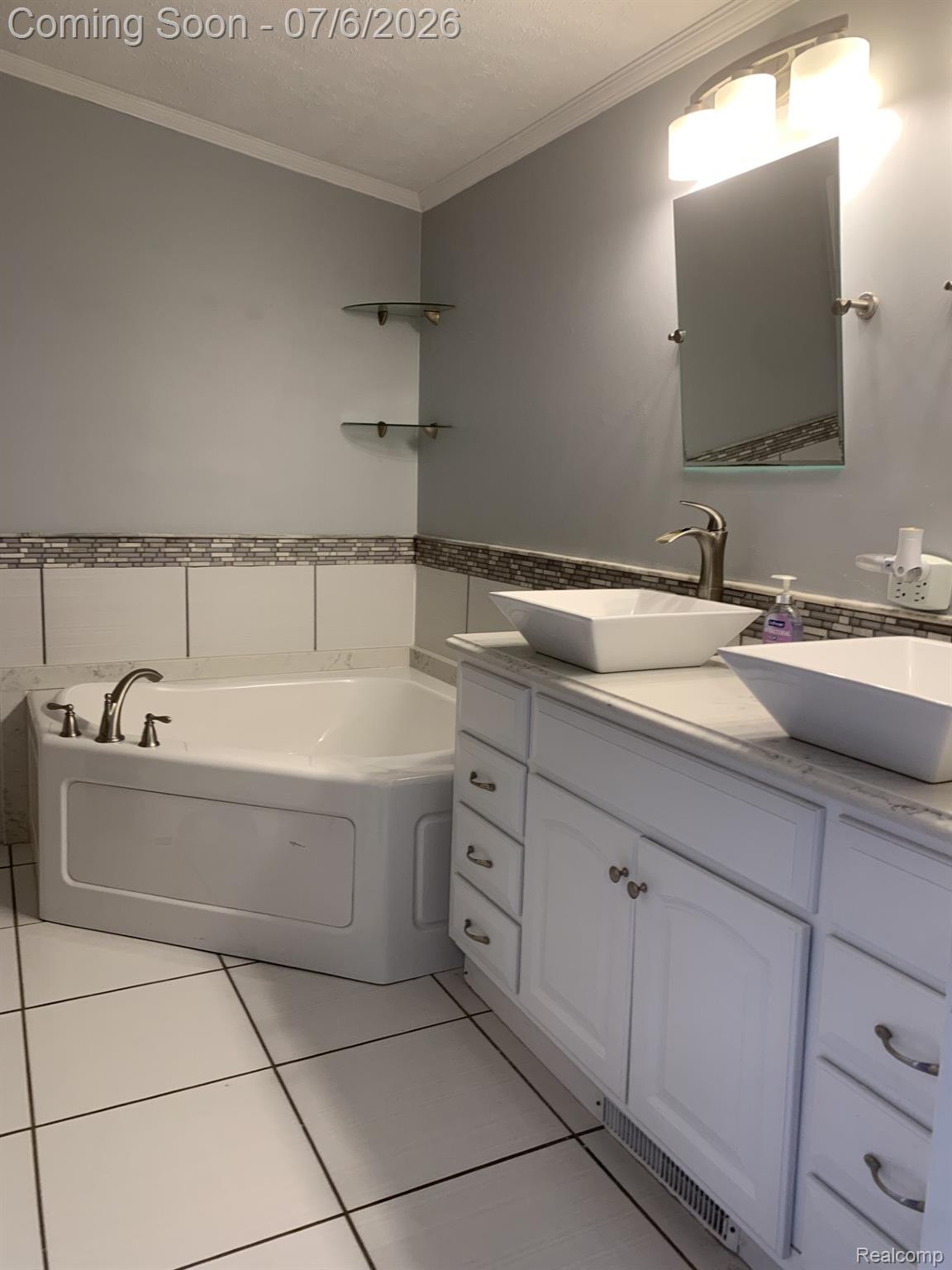 4168 Harris Road Fort Gratiot, MI 48059 - Photo 27 of 30 Bathroom featuring a corner soaking tub with brushed nickel fixtures, a dual vanity with vessel sinks, white shaker-style cabinetry, and a full wall mirror with integrated lighting