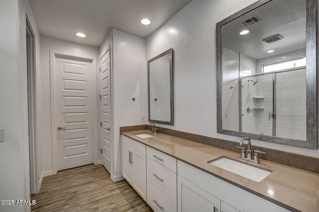 a bathroom with a double vanity sink a mirror and a shower