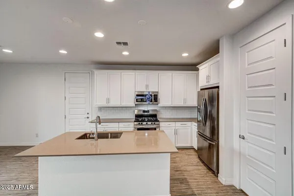 a kitchen with kitchen island a white counter top space cabinets and stainless steel appliances