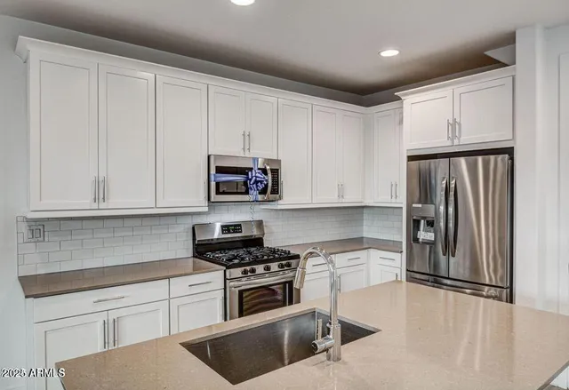 a kitchen with white cabinets and stainless steel appliances
