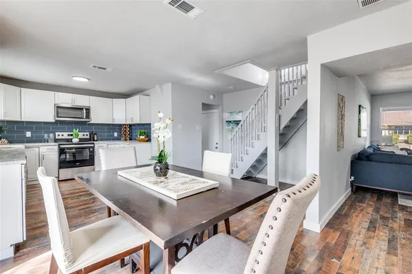 a living room with stainless steel appliances furniture a rug and a kitchen view