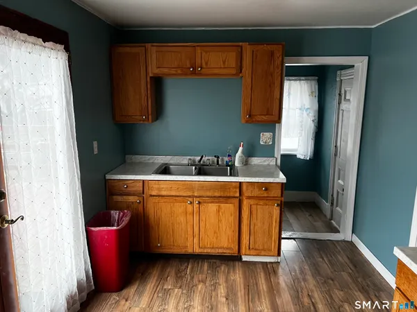 a room with stainless steel appliances wooden floors sink and cabinets