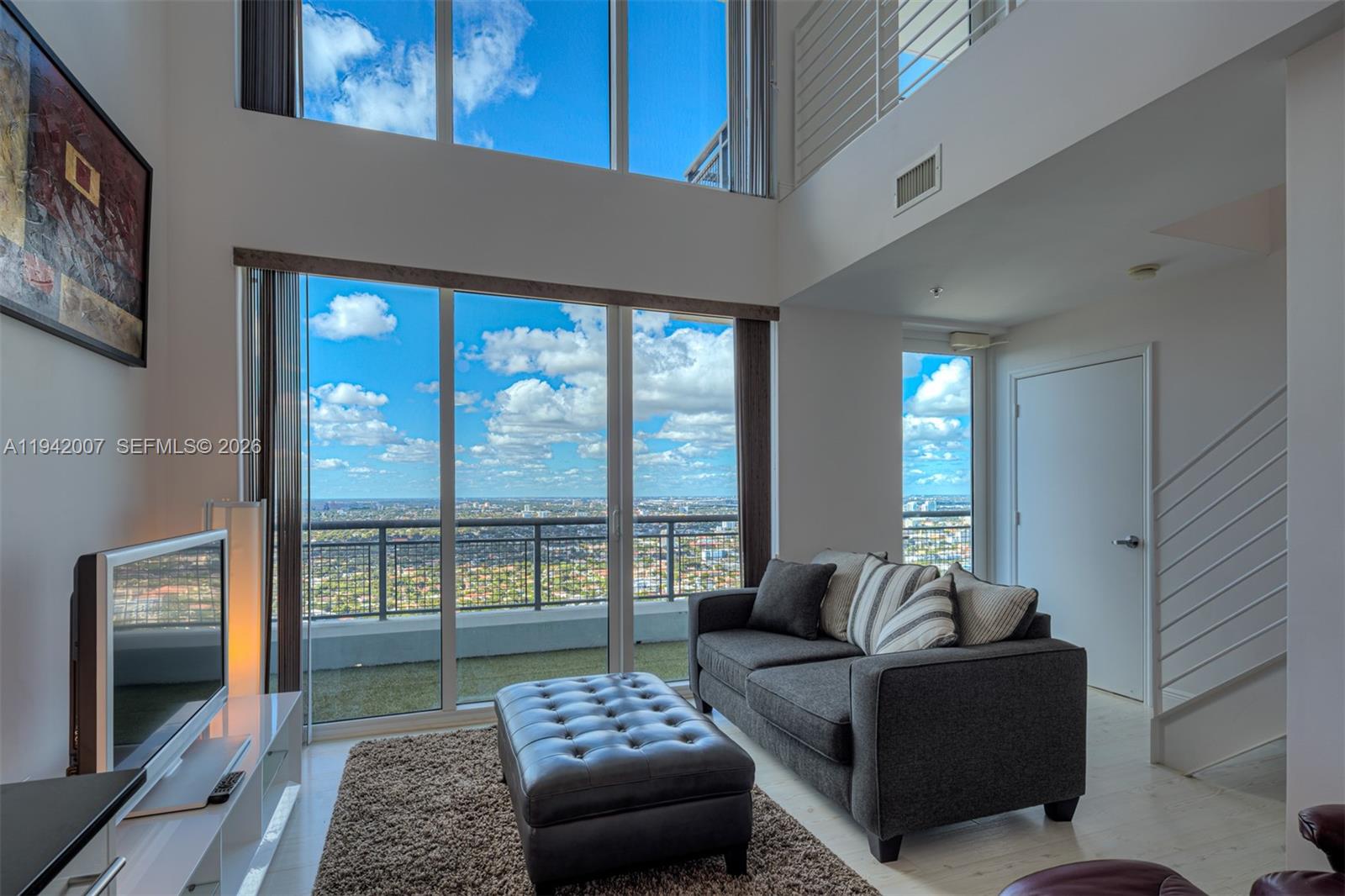 60 Southwest 13th Street, Unit 4211 Miami, FL 33130 - Photo 2 of 17 a living room with furniture and a floor to ceiling window