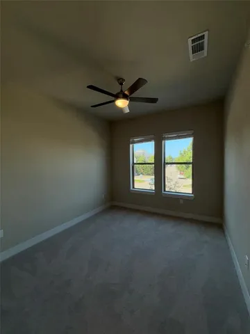 an empty room with a ceiling fan and a window