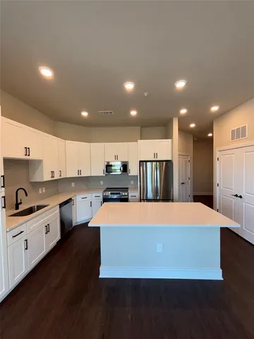 a large kitchen with kitchen island a sink stainless steel appliances and cabinets