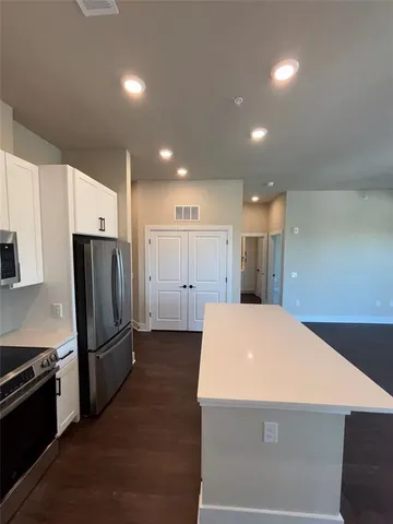 a view of a kitchen with a refrigerator and a stove top oven