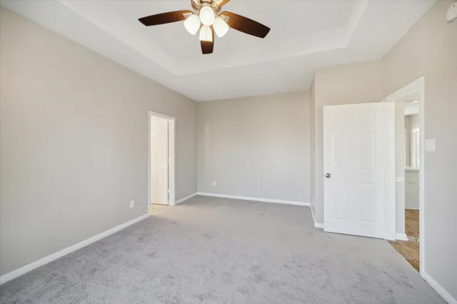 an empty room with chandelier fan and windows