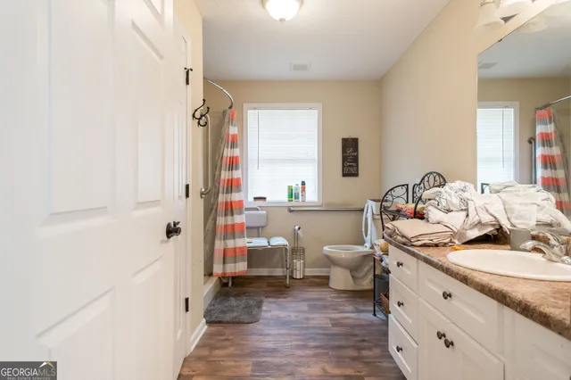 a bathroom with a granite countertop sink a toilet and shower