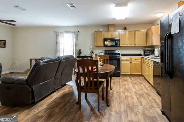 a kitchen with stainless steel appliances granite countertop a table chairs microwave and sink