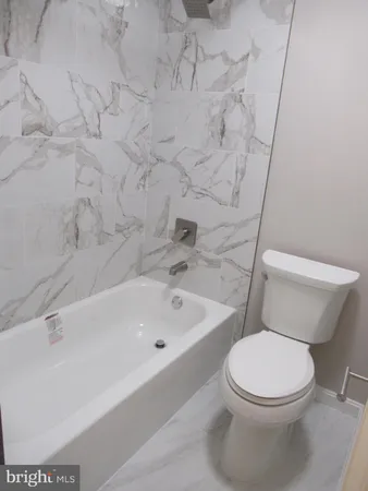 a white toilet sitting next to a bath tub