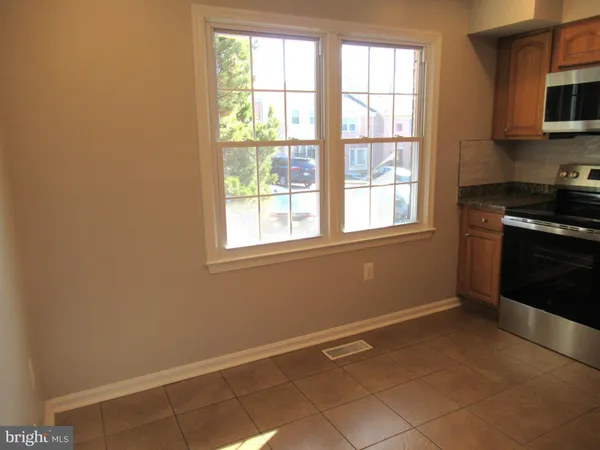 a view of an empty room with a window and a kitchen