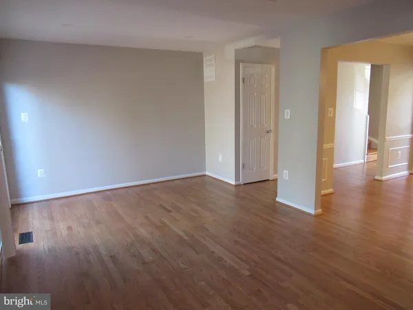 an empty room with wooden floor & windows