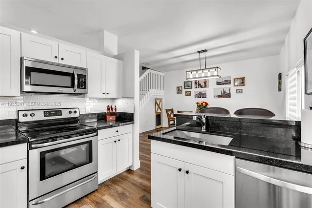 a kitchen with granite countertop white cabinets and stainless steel appliances
