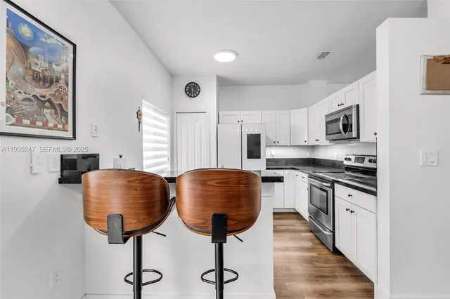 a kitchen with stainless steel appliances granite countertop a microwave a stove and white cabinets