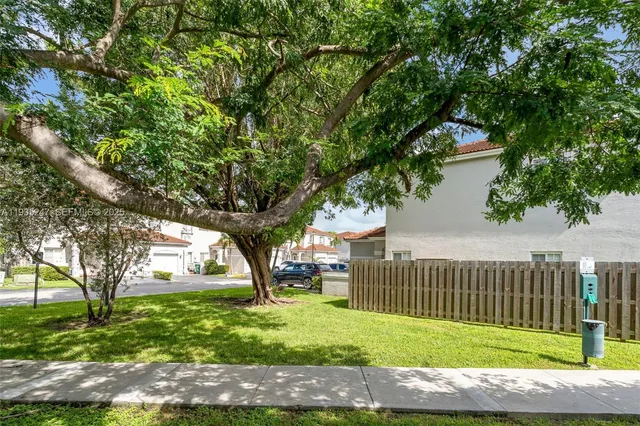 a view of a house with a small yard and a large tree