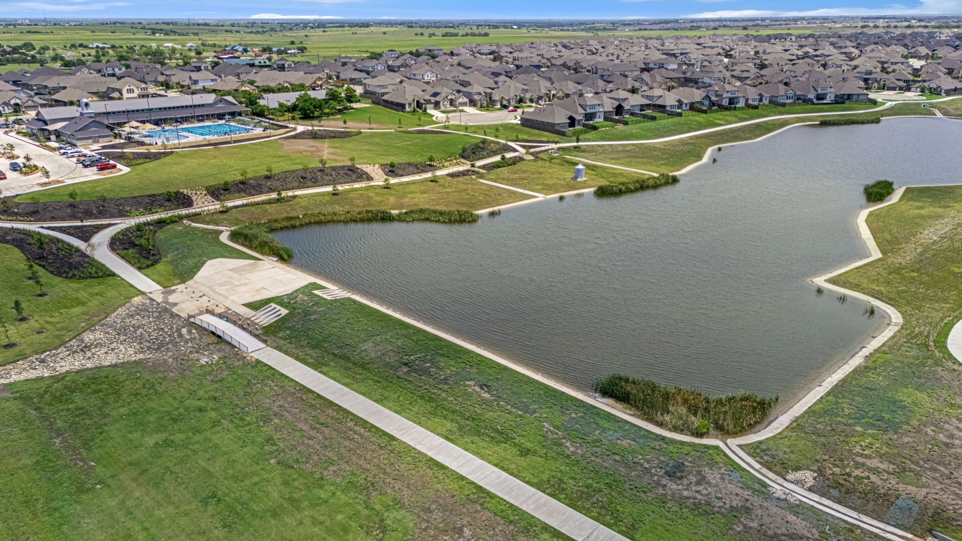 17200 Hope Bergman Road Pflugerville, TX 78660 - Photo 3 of 27 Lush landscaping and winding pathways surround a serene lake, complementing a vibrant community pool and clubhouse.
