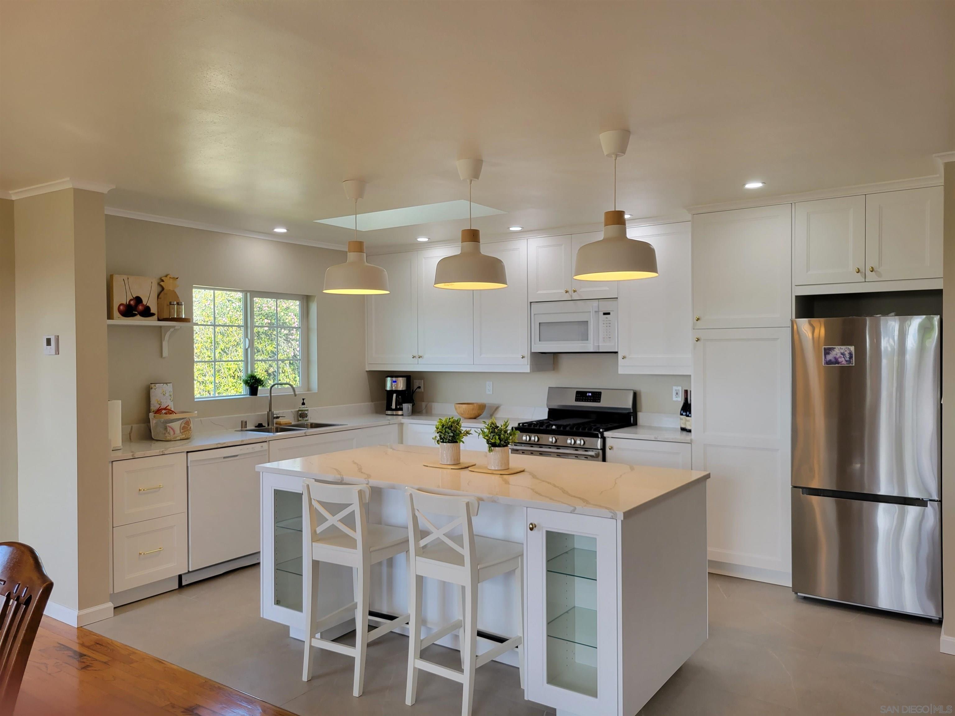 a kitchen with stainless steel appliances a sink a stove a refrigerator cabinets and a dining table