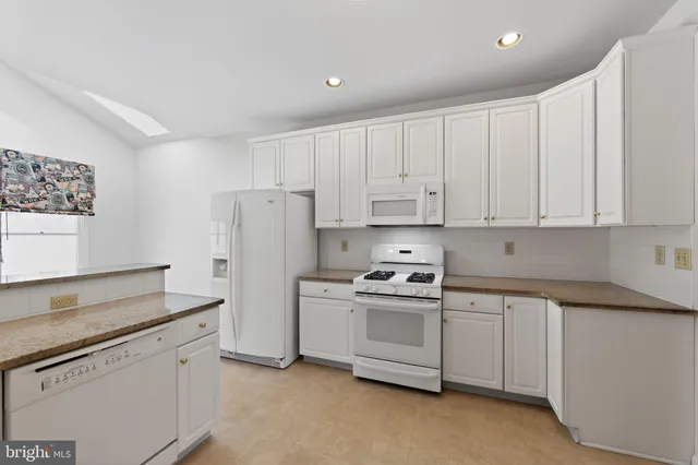 a kitchen with white cabinets and white appliances