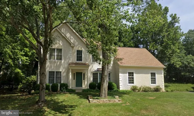a view of a white house with a big yard and potted plants and trees