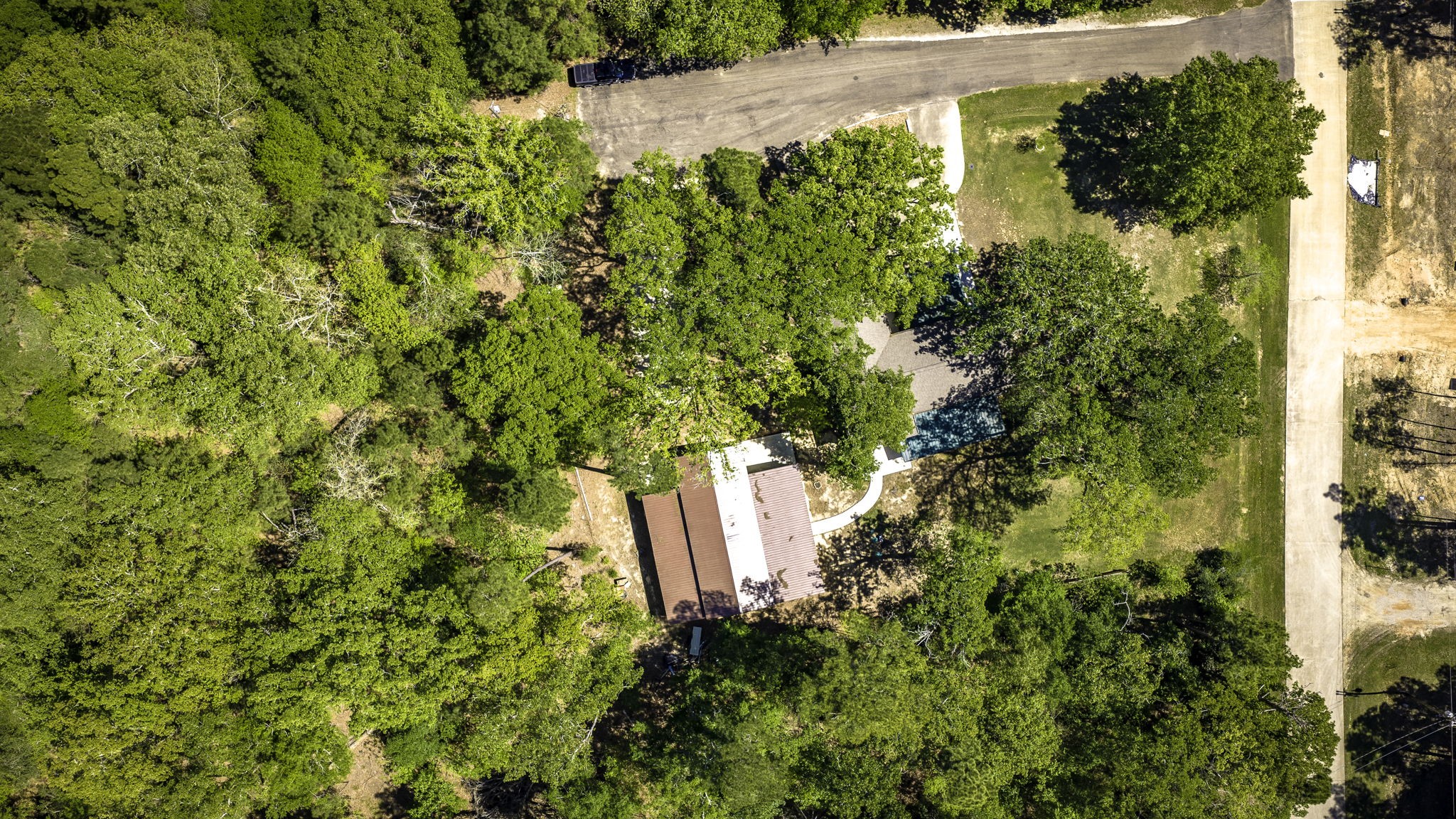 21 Red Oak Circle Point Blank, TX 77364 - Photo 31 of 32 This aerial photo shows a house surrounded by lush greenery, offering privacy and a sense of seclusion. The property is bordered by a paved road and features a large driveway with ample outdoor space.