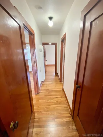 an empty room with wooden floor chandelier fan and windows