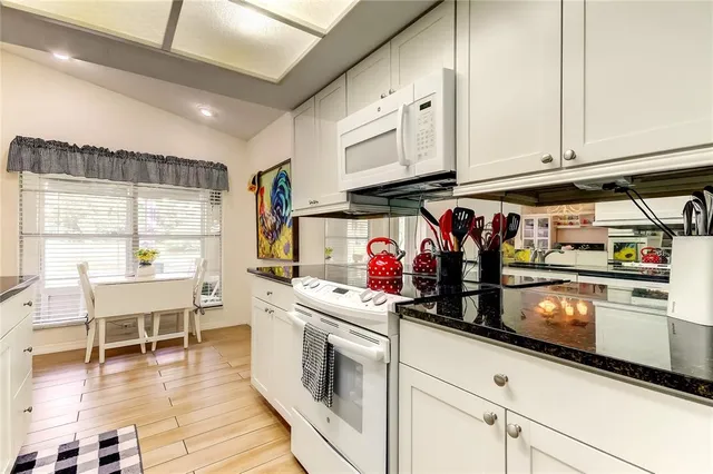 a kitchen with stainless steel appliances granite countertop a stove and white cabinets
