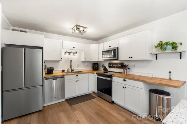 a kitchen with a sink stainless steel appliances and white cabinets