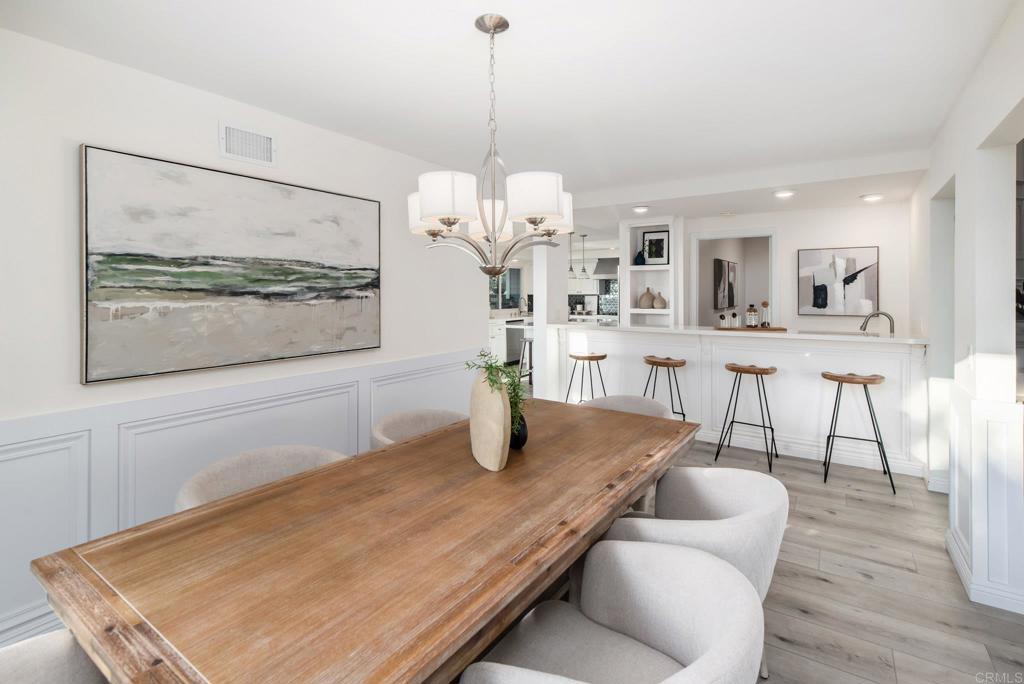 2515 Luciernaga Street Carlsbad, CA 92009 - Photo 10 of 58 a dining room with wooden floor a chandelier a glass table and chairs