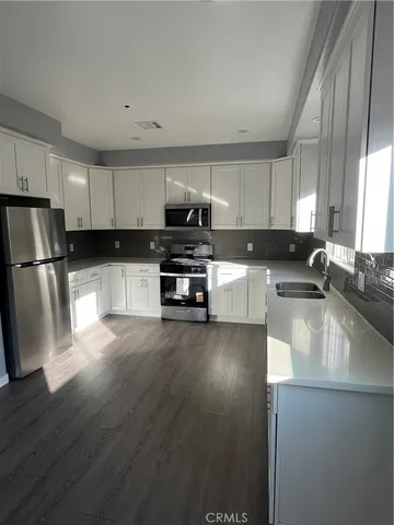 a kitchen with granite countertop a refrigerator a stove top oven a sink and dishwasher with wooden floor