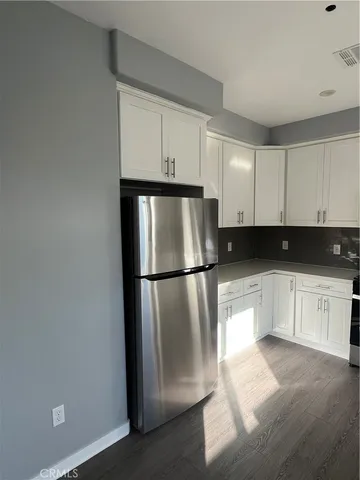 a kitchen with a refrigerator and white cabinets