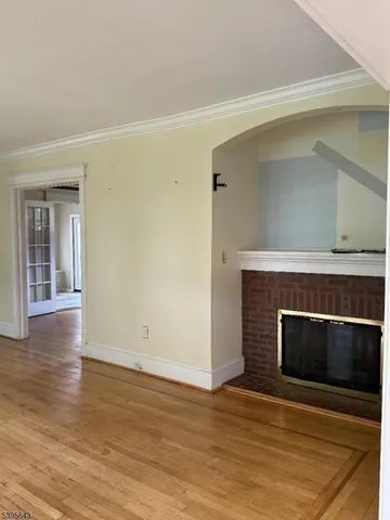 a view of an empty room with wooden floor and a fireplace