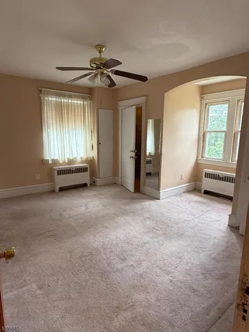 an empty room with windows and fan