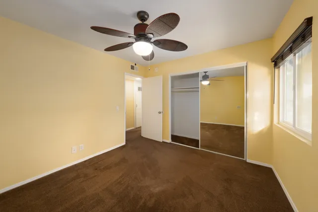 an empty room with closet and chandelier fan