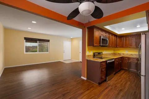a large kitchen with stainless steel appliances granite countertop a stove and a wooden floors