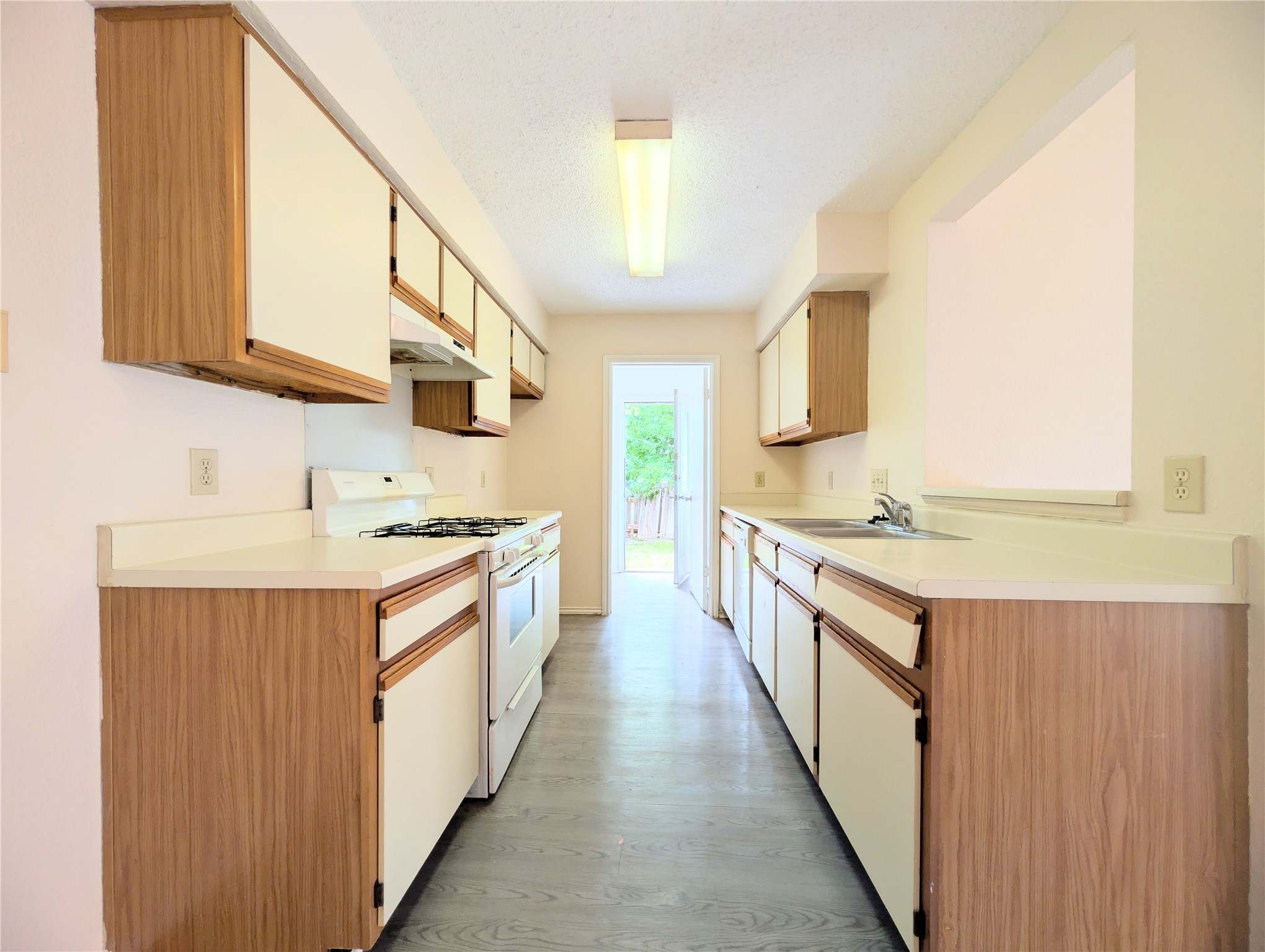2018 Redwing Way Round Rock, TX 78664 - Photo 11 of 27 Galley kitchen featuring wood-finish cabinetry with white panels, white countertops, and white appliances