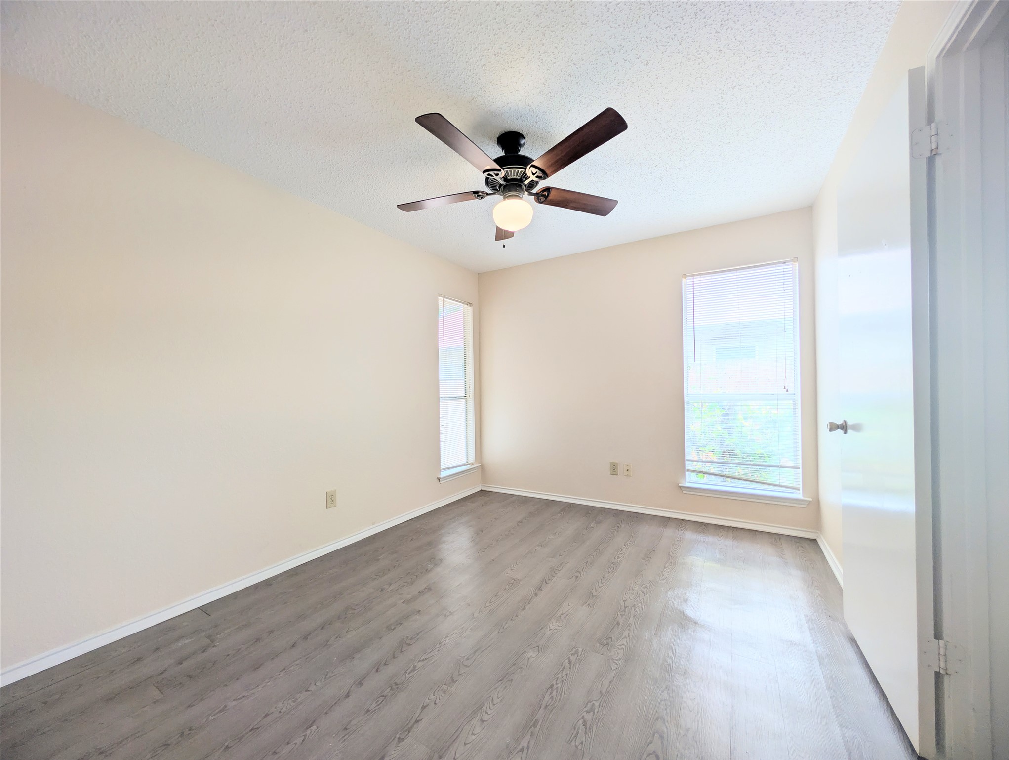 2018 Redwing Way Round Rock, TX 78664 - Photo 15 of 27 Guest Bedroom #1 Interior space featuring wood-finish flooring, two window openings, and a ceiling fan with integrated lighting