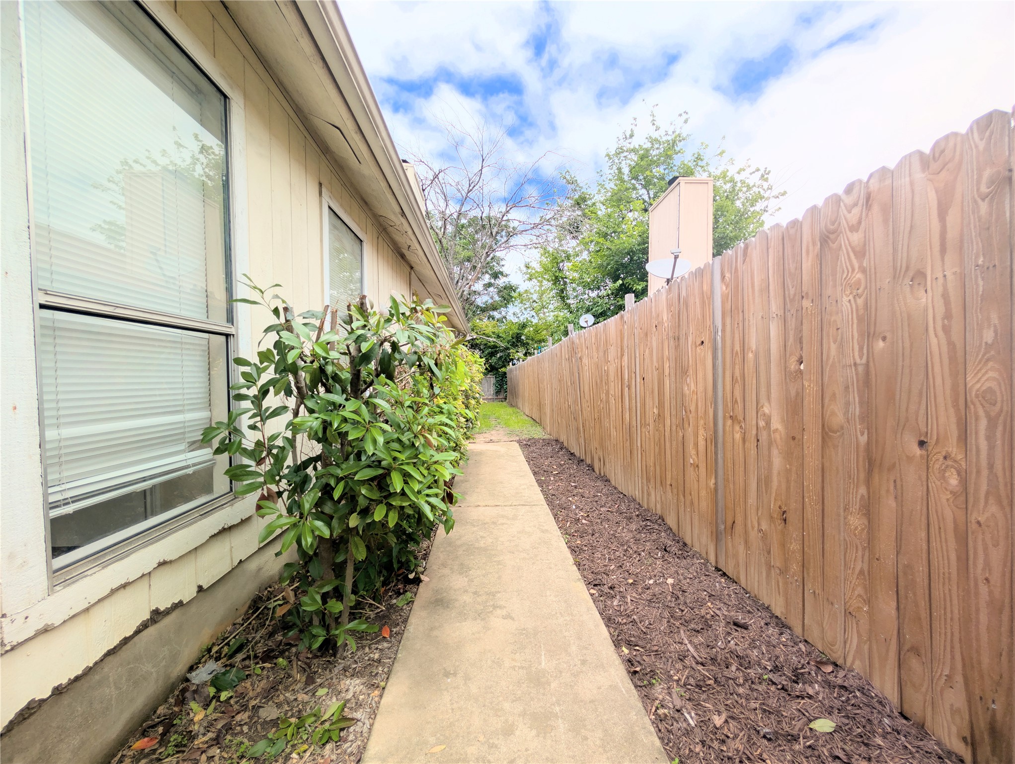 2018 Redwing Way Round Rock, TX 78664 - Photo 5 of 27 Side yard featuring a concrete pathway, privacy fence, and established shrubbery along the building