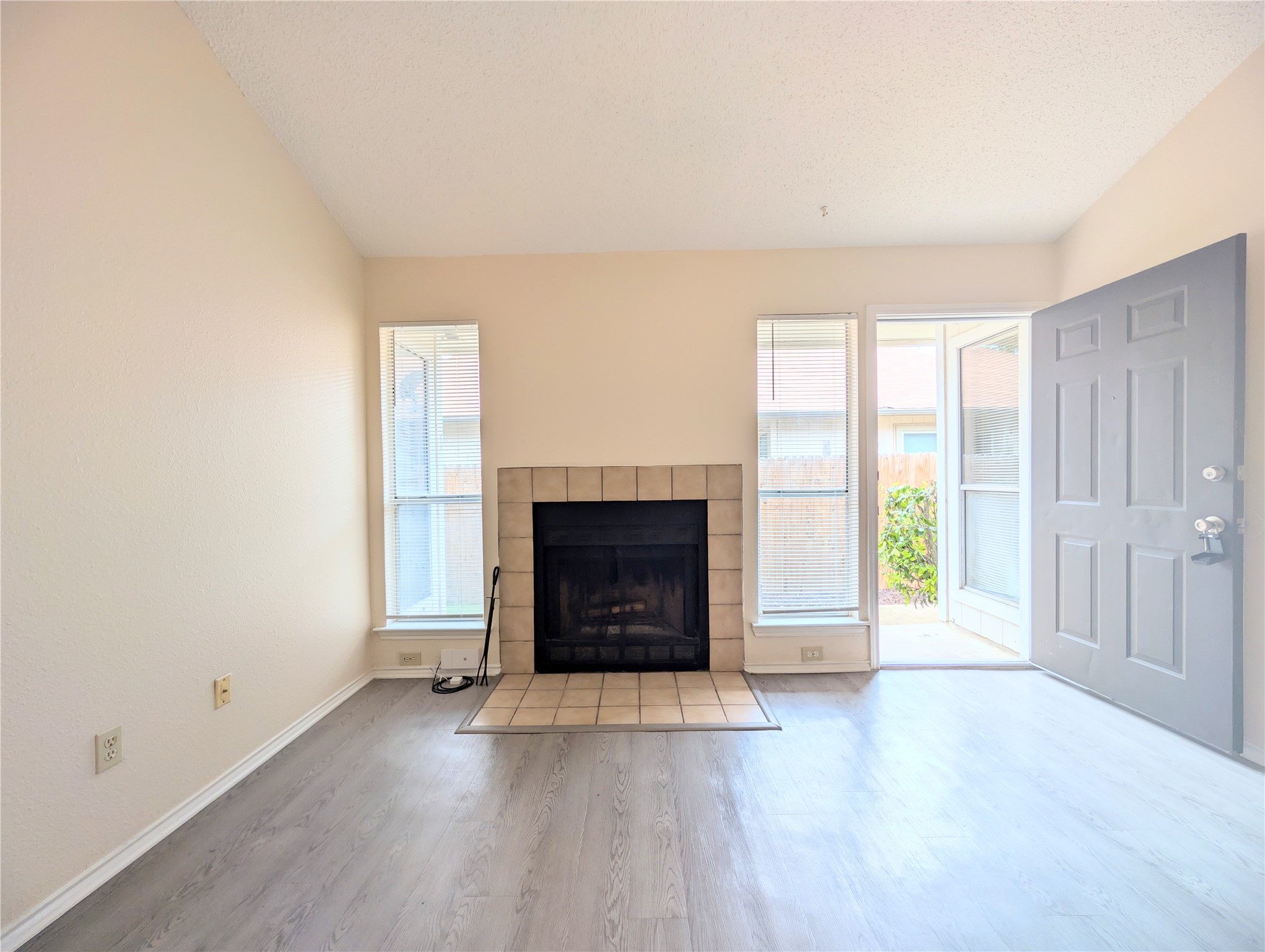 2018 Redwing Way Round Rock, TX 78664 - Photo 8 of 27 Living area featuring a tiled fireplace, wood-finish flooring, and a paneled entry door
