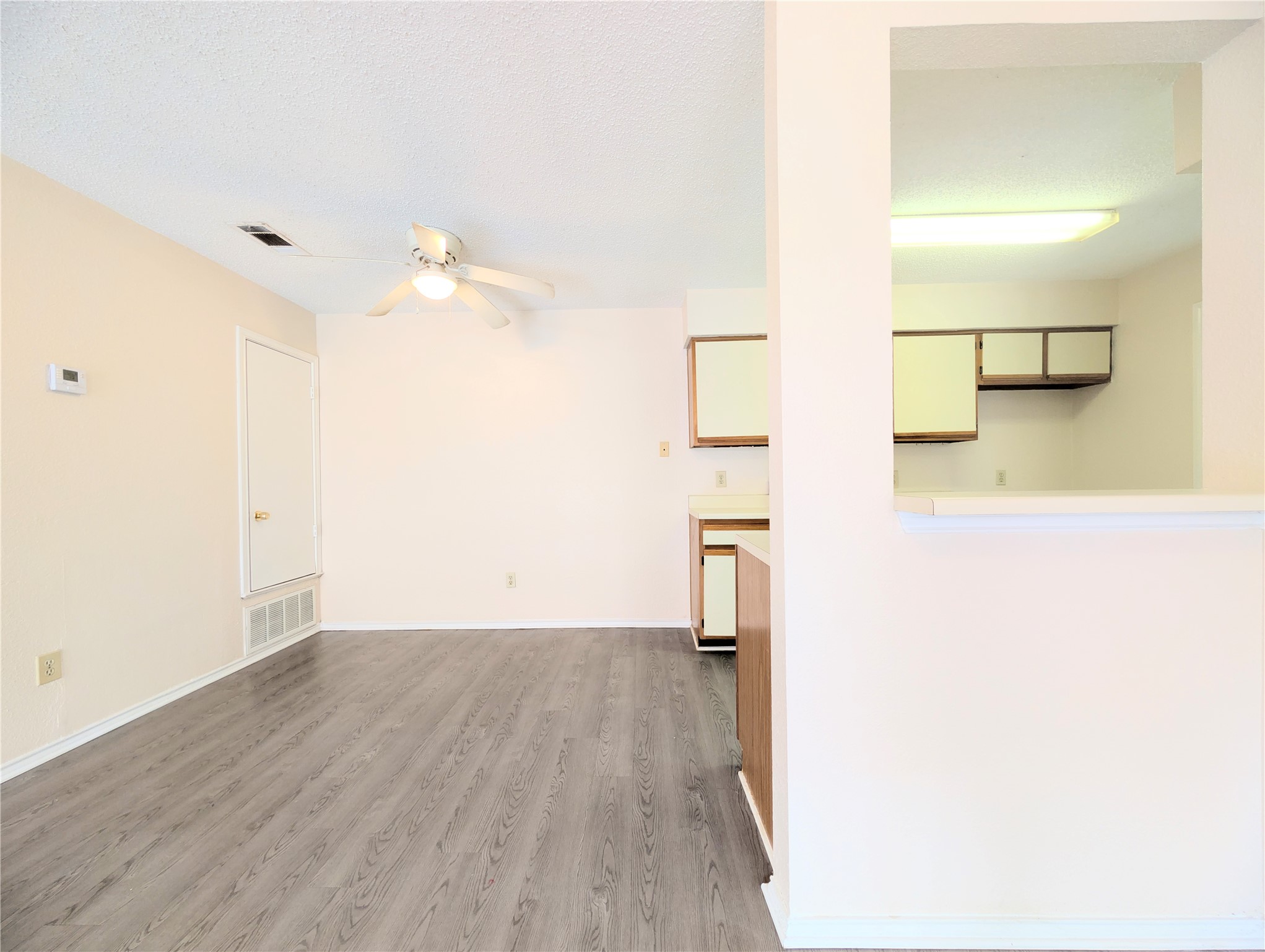 2018 Redwing Way Round Rock, TX 78664 - Photo 9 of 27 Living area featuring wood-finish flooring, a ceiling fan with integrated lighting, and a partial wall opening to the kitchen