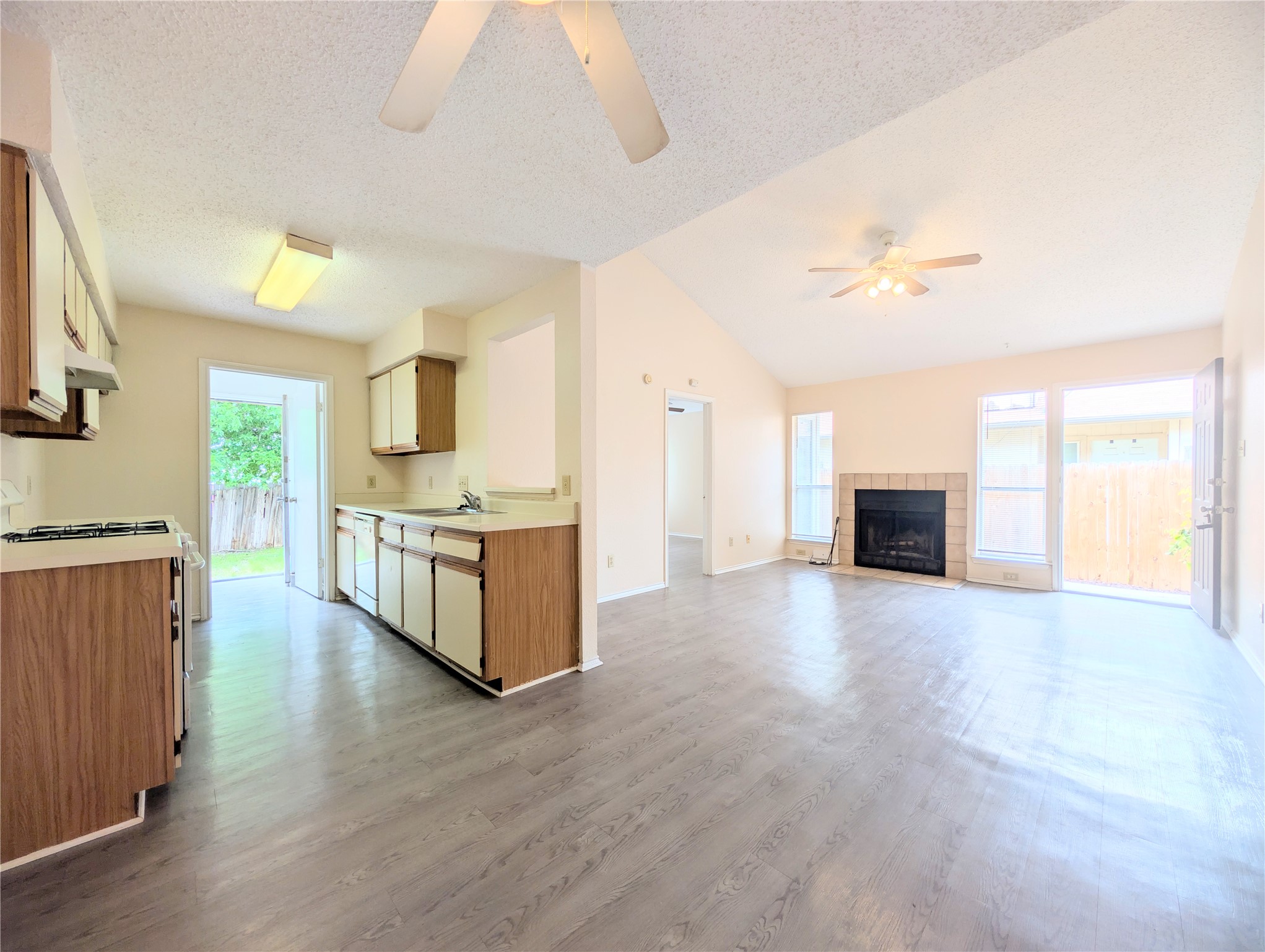 2018 Redwing Way Round Rock, TX 78664 - Photo 10 of 27 Open concept living space featuring wood-finish flooring, vaulted ceilings, and a fireplace with a tile surround