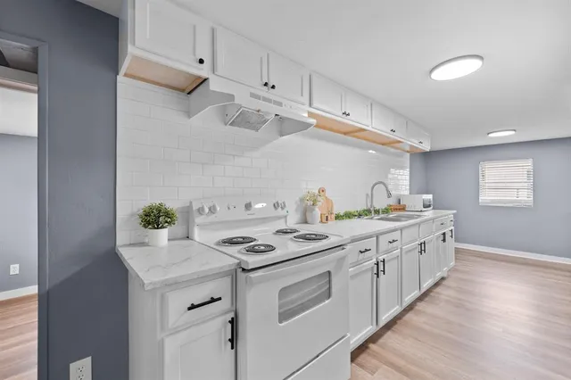 a kitchen with granite countertop a sink stove and cabinets