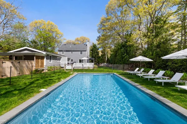 a view of swimming pool with lawn chairs under an umbrella