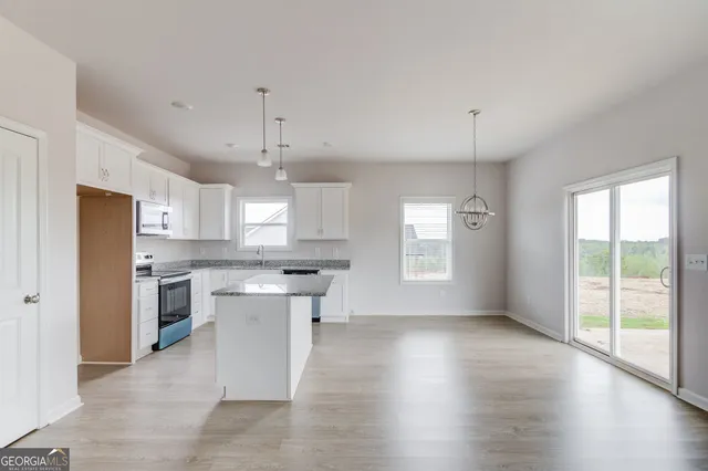 a kitchen with stainless steel appliances granite countertop a sink a stove a refrigerator and white cabinets
