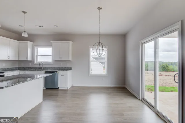 a kitchen with stainless steel appliances a stove a sink dishwasher a refrigerator and white cabinets with wooden floor