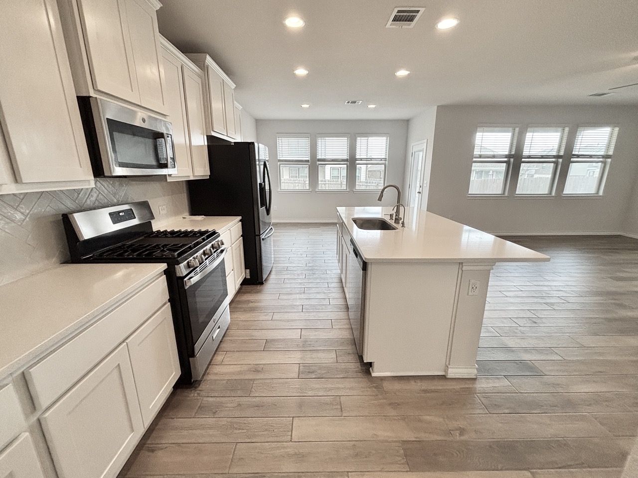 7606 Elk Grove Path Austin, TX 78754 - Photo 39 of 40 Kitchen with appliances with stainless steel finishes, an island with sink, recessed lighting, open floor plan, and white cabinets