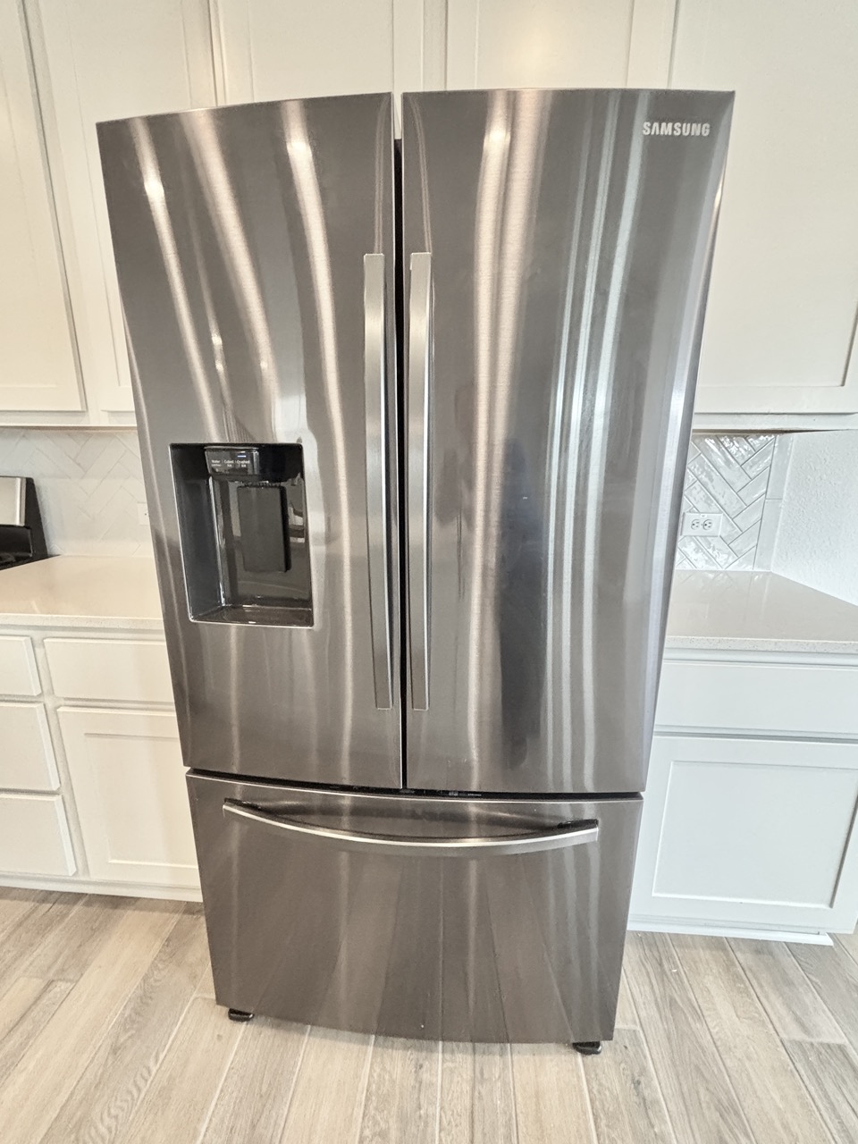 7606 Elk Grove Path Austin, TX 78754 - Photo 13 of 40 Kitchen view of stainless steel refrigerator with ice dispenser, white cabinetry, decorative backsplash, light wood-style floors, and light stone counters